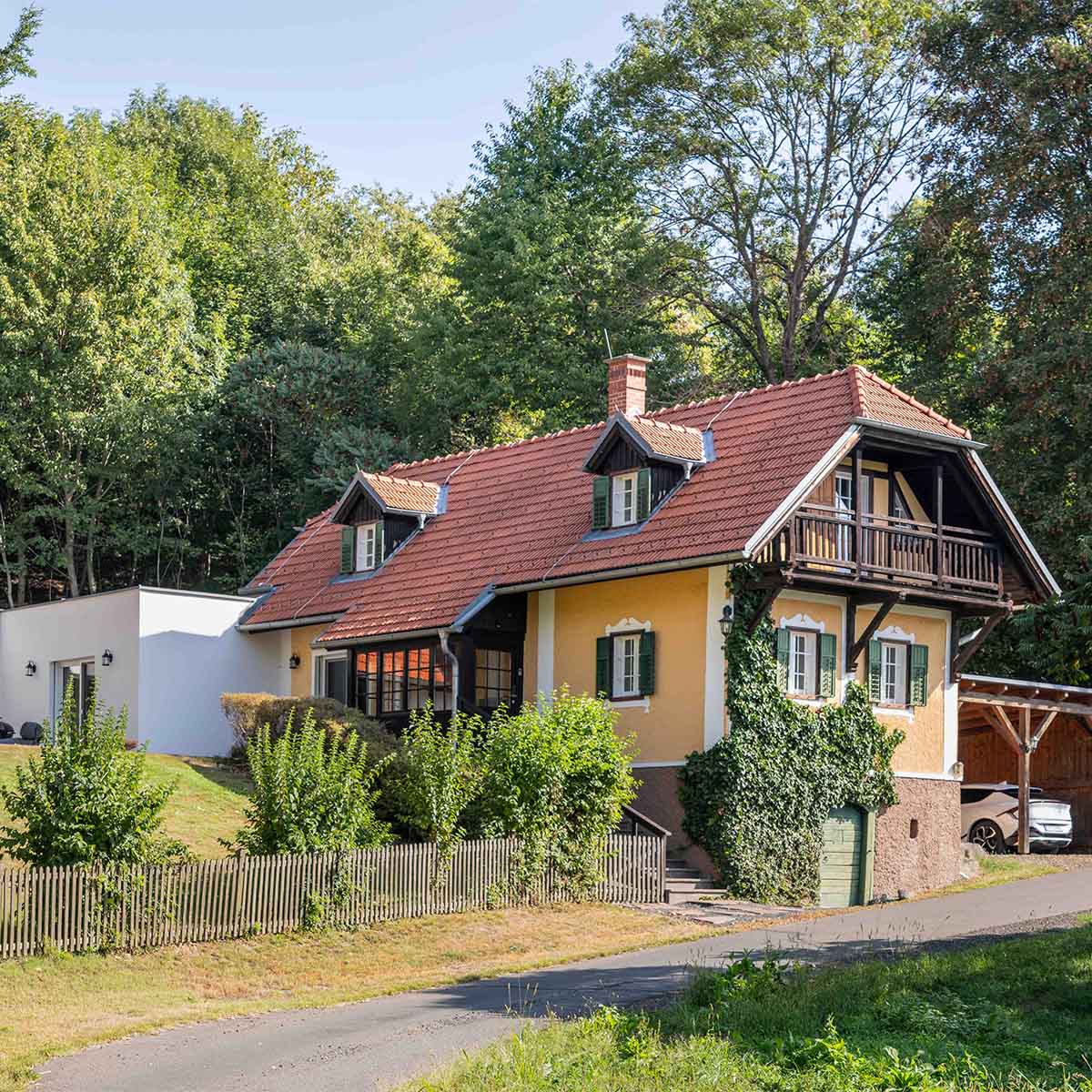 Traminerhaus — Straßenseite mit Holzbalkon & grünen Fensterläden